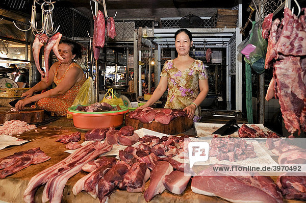 Marktfrau an einem Marktstand mit verschiedenen Fleischstücken  Waren hängen auf Metallhaken in der Luft  Fleischmarkt  Vinh Long  Mekongdelta  Vietnam  Asien