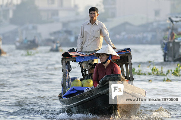Ein Mann und eine Frau mit vietnamesischen Kegelhut  Handelsboot fährt am Mekong  Mekongdelta  Vietnam  Asien