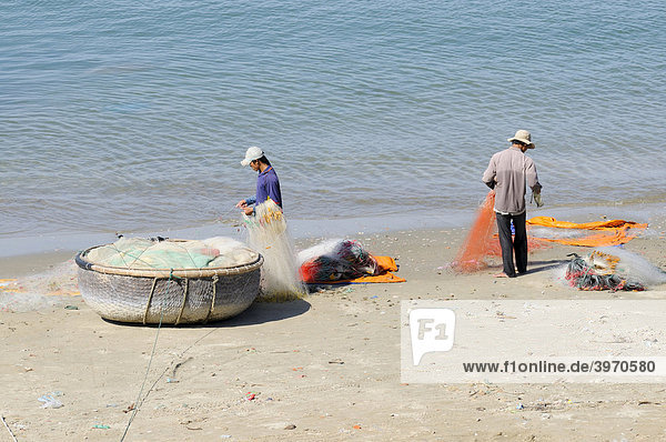 Two fishermen on a beach repairing their fishing nets  Mui Ne  Vietnam  Asia