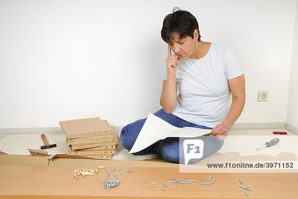 Woman assembling furniture  reading the instructions