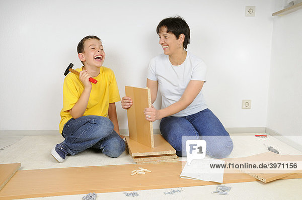 Mutter und Sohn beim Möbel zusammenbauen  Montage Regal-Brett