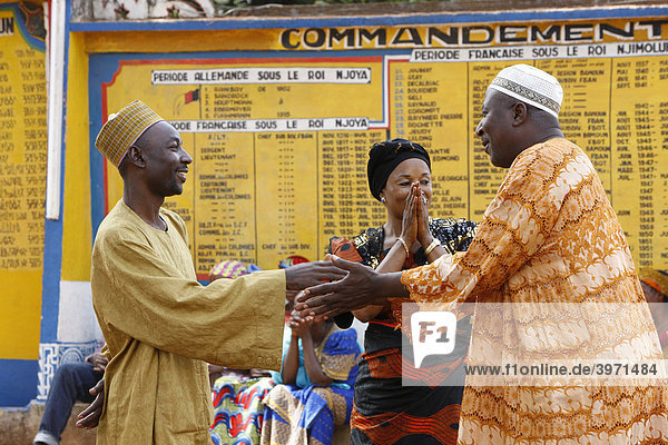 Begrüßung vor dem Sultanspalast  warten auf Audienz beim Sultan  dahinter Tafeln zur Geschichte der Bamundynastie  Foumban  Kamerun  Afrika
