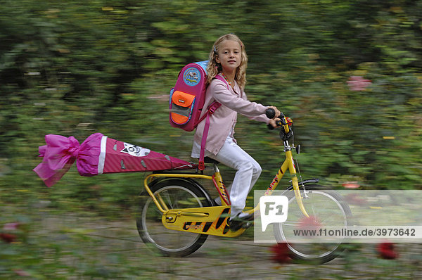 Sechsjähriges Mädchen mit Schultüte auf dem Fahrrad  Einschulung