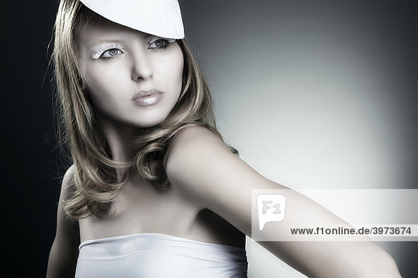 Fashionaufnahme einer jungen Frau im weißen Kleid mit Hut