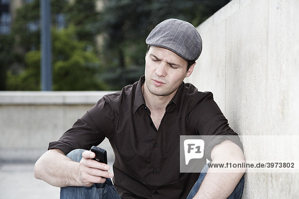 Junger Mann liest auf seinem Handy eine SMS