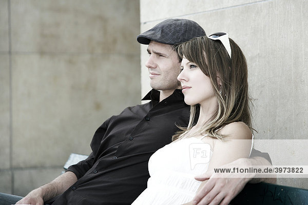 Junges Paar sitzt gemeinsam auf einer Parkbank