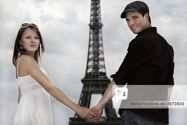 Junges Paar  Hand in Hand vor dem Eiffelturm  Paris  Frankreich  Europa