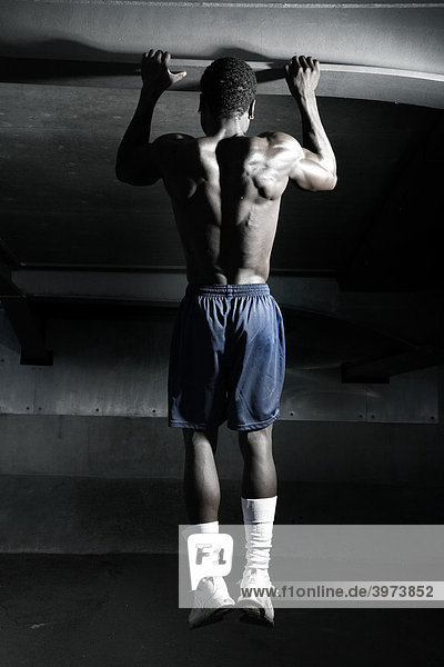 Young dark-skinned athlete  doing pull-ups