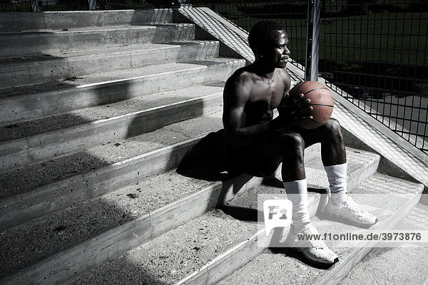 Dark-skinned basketball player sitting on stairs