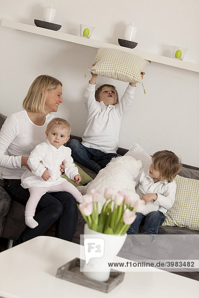 Mutter und drei Kinder  1  3 und 6 Jahre  toben auf Couch