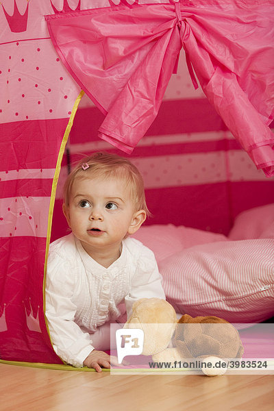 Kleines Mädchen  1-jährig  schaut aus pinkfarbenem Spielzelt heraus