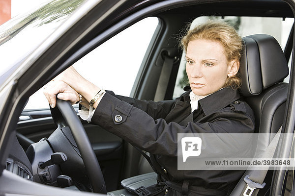 Woman behind the steering wheel of a luxury cross country vehicle  pensive