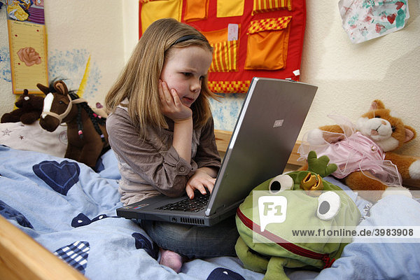 Girl  7 years old  working with a computer at home in her room  sitting on her bunk bed  doing homework for school  educational software