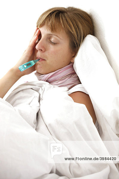 Young woman  sick in bed with fever  measuring her body temperature with a digital thermometer