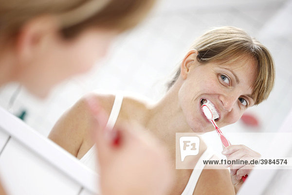 Junge Frau putzt sich in einem Badezimmer die Zähne