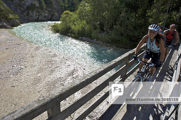 Montainbike riders  female and male  on a wooden bridge  crossing the Isar River near the Wiesenhof Hotel  near Scharnitz  Tyrol  Austria  Europe