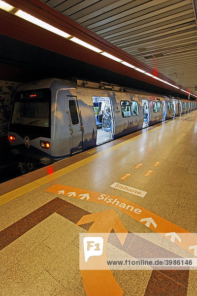 U-Bahn wartet mit geöffneten Türen am Bahnsteig  großer Richtungspfeil am Boden  moderne Metro-Station Taksim-Platz  Beyoglu  Istanbul  Türkei