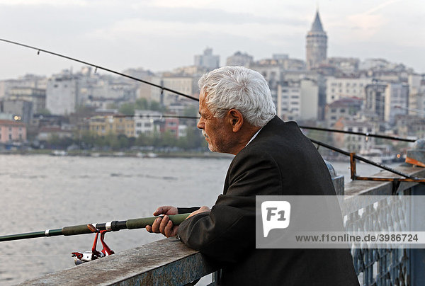 White haired Turkish angler on the Galata Bridge  evening sun  Eminoenue  Istanbul  Turkey
