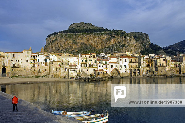 Alter Hafen vor dem Berg La Rocca  Fischerboote  Mann in roter Jacke  maurische Architektur in der Stadt Cefalu  Provinz Palermo  Sizilien  Italien