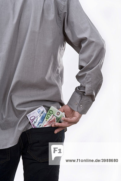 Euro banknotes sticking out of the trouser pocket of a young man