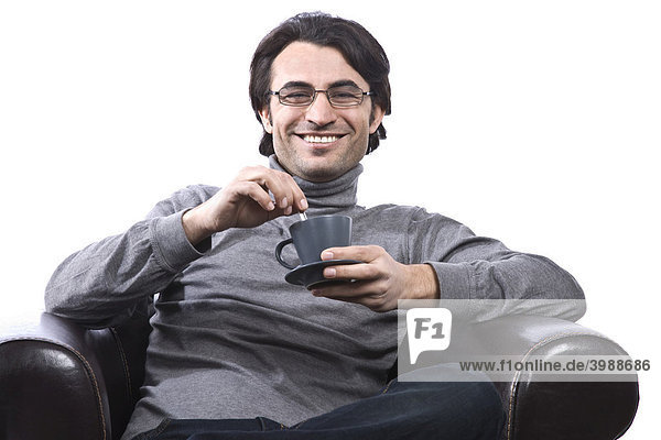 Young man sitting on a leather armchair with a cup of coffee