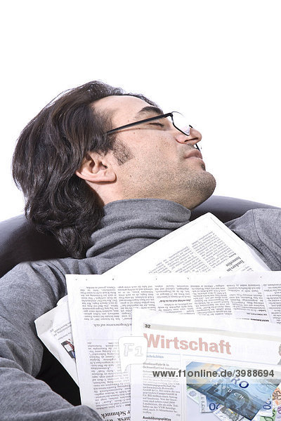 Young man sleeping on a leather armchair with a newspaper