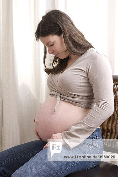Schwangere Frau betrachtet ihren Bauch