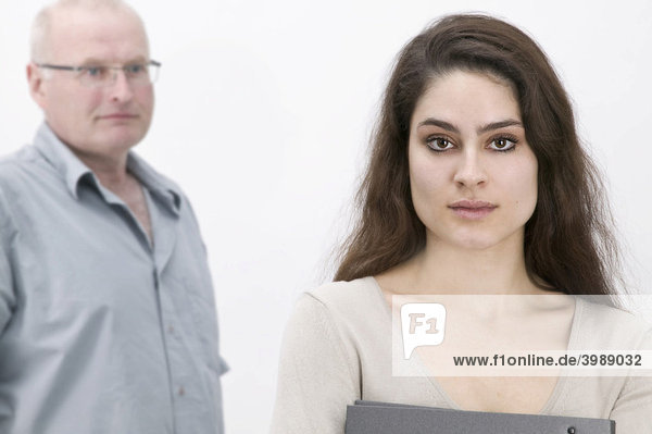 Girl holding a file  serious looking man in the back