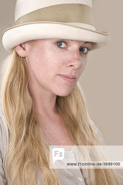 Junge blonde Frau mit Hut blickt interessiert