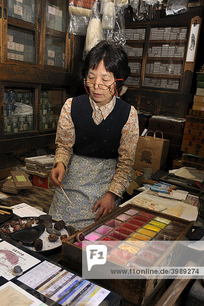 Verkäuferin demonstriert kniend auf einer Tatamimatte verschiedene Mineralfarben für Nihonga-Malerei in einem traditionellen Geschäft für Künstlerbedarf  Kyoto  Japan  Asien