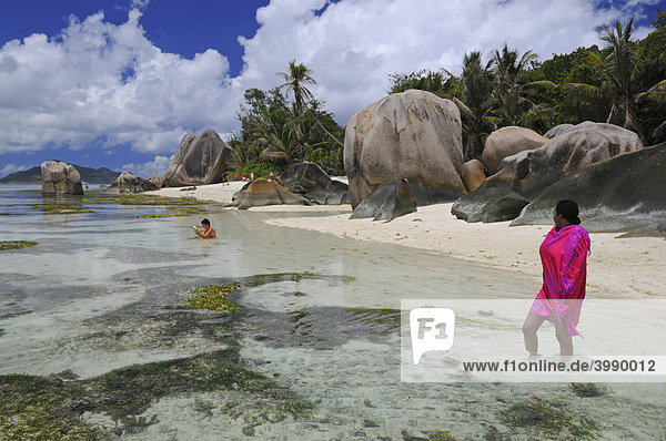 Kreolin mit rosa Strandtuch im seichten Wasser  Anse Source D'Argent  La Digue  Seychellen