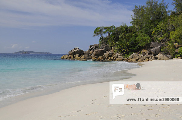 Woman lying on a beach with granite rocks and tropical vegetation  Anse Georgette  Praslin Island  Seychelles  Africa  Indian Ocean