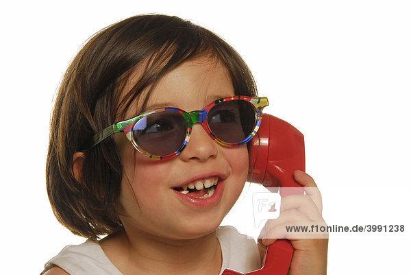 Vierjähriges Mädchen mit Telefonhörer und Sonnenbrille