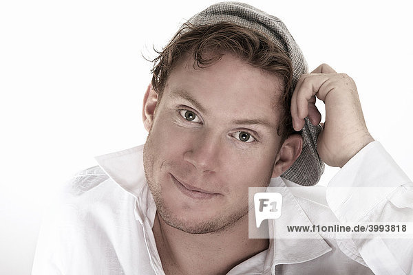 Portrait eines jungen  lächelnden Mannes im weißen Hemd und Mütze