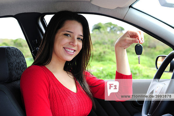 Smiling woman seated at the wheel of a car showing her car keys