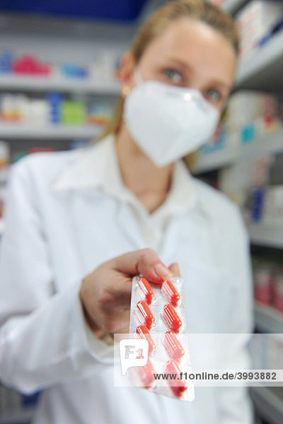 Pharmacist wearing a face mask while handing medicine to a customer