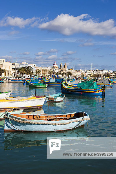 Traditionelle maltesische Fischerboote im Hafen von Marsaxlokk  hinten die Kirche Lady of Pompei  Malta  Europa