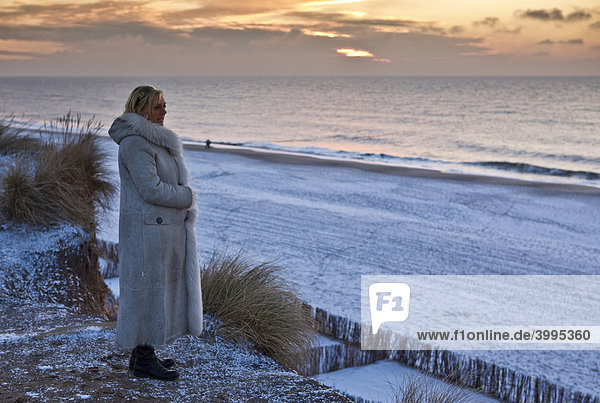 Sylt im Winter  Frau steht am Roten Kliff und schaut den Sonnenuntergang an  Kampen  Sylt  nordfriesische Insel  Schleswig-Holstein  Deutschland  Europa