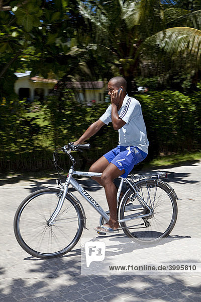 Einheimischer Fahrradfahrer mit Handy  Insel La Digue  Seychellen  Indischer Ozean  Afrika