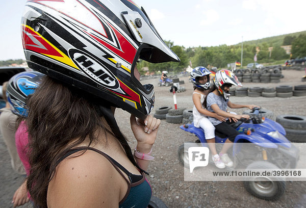 Mädchen  ca 16 Jahre  mit einem Helm schaut auf eine Quadbahn  Kinder fahren auf Quad  Hessen  Deutschland  Europa