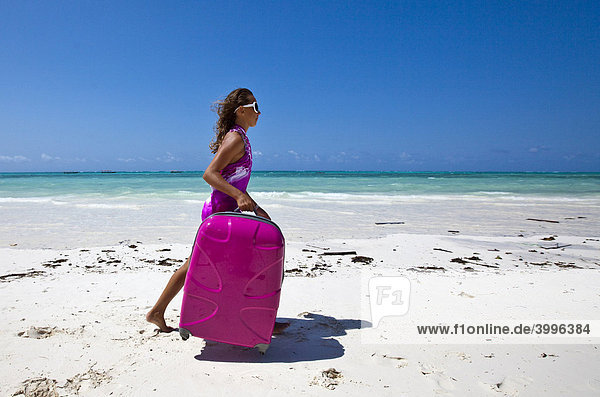 Kind mit Koffer läuft im Urlaub am Strand