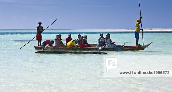 Ein Fischerboot bringt bunt gekleidete Frauen an den Strand  Sansibar  Tansania  Afrika