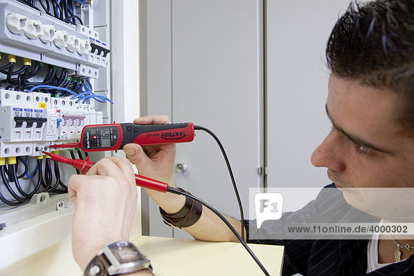 Master electrician student using a voltmeter on a VDE measuring station  control panel  fuse box  master electrician from the Master Craftman School of the Chamber of Small Industries and Skilled Trades  Dusseldorf  North Rhine-Westphalia  Germany  Europe