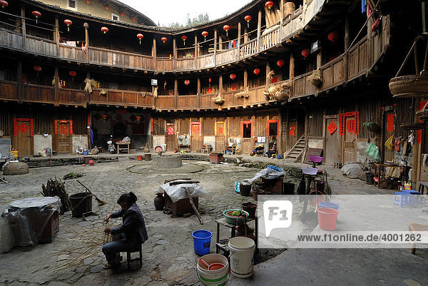 Chinesische Korbflechterin sitzt im Innenhof eines Rundhauses  chinesisch: Tulou  Lehmrundhaus der Hakka Minderheit  Tianluokeng Building Group  Hukeng  Fujian  China  Asien