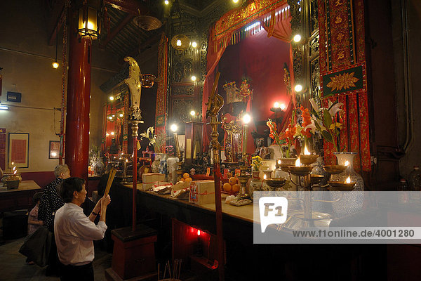 Man and woman praying with incense sticks  smoke sacrifice  in front of a Chinese Buddhist altar with burning candles and offerings in the Man Mo Temple  Hong Kong  China  Asia