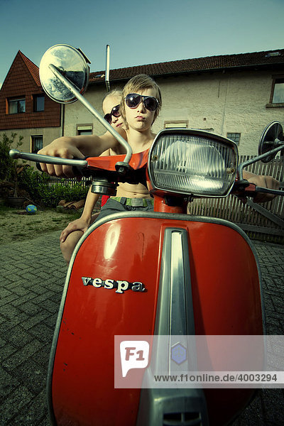 Junge und Mädchen auf Motorroller