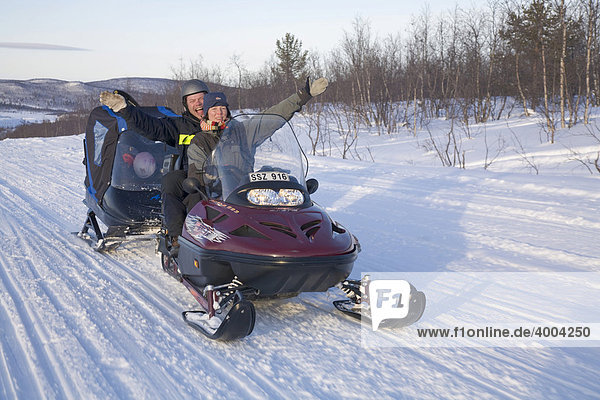 Eine Frau und ein Mann in den Vierzigern auf einer Schneemobil-Tour in Kiruna  Lappland  Nord-Schweden  Schweden
