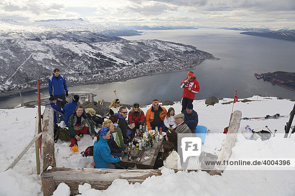 A group of day-trippers sitting high above Narvik and Ofotfjord on Fagernes-Fjellet Mountain in the snow  Narvik  Norway  Europe