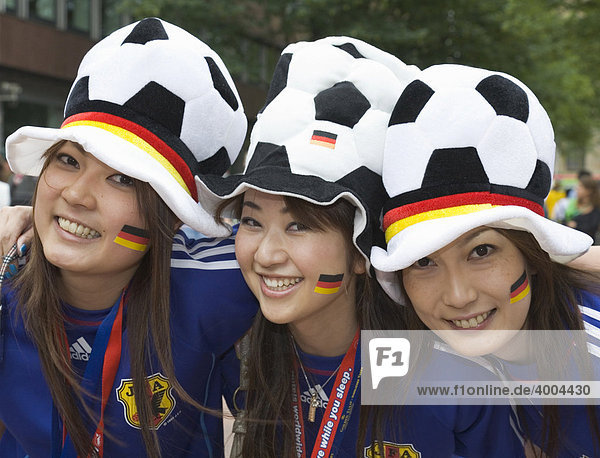 Drei weibliche japanische Fußballfans posieren gut gelaunt mit Kopfbedeckungen und Stickern in deutschen Landesfarben vor dem Spiel der Fußball-Weltmeisterschaft 2006 Japan gegen Brasilien  1:4  in Dortmund  Nordrhein-Westfalen  Deutschland