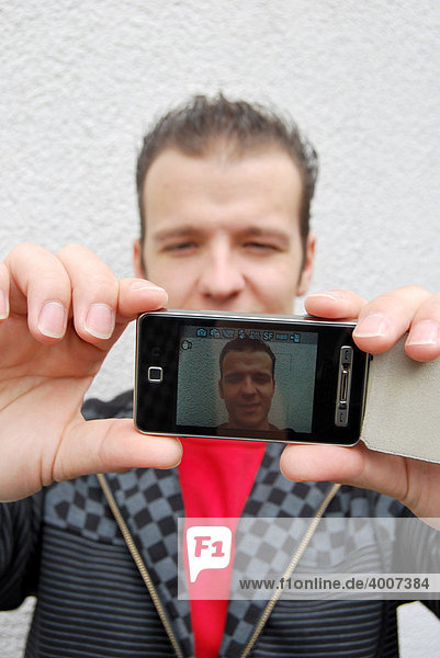 Selbstportrait  junger Mann fotografiert sich mit der Handycam  Handykamera